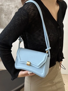 Minimalist light blue saddle shoulder bag with gold buckle shown on a model