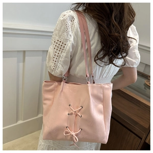 Detail of pink tote bag featuring a decorative cross-lace bow and fine textured synthetic leather