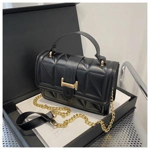 Detail of black faux leather handbag with geometric quilting and gold metallic buckle