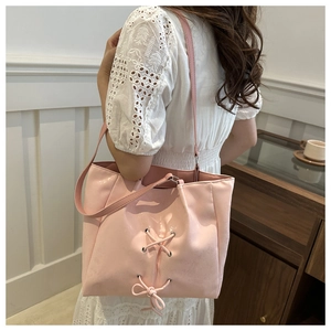 Pink tote bag with bow detail shown on shoulder for a stylish casual commuter look