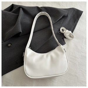 Detailansicht der weißen Halbmond-Achseltasche mit abnehmbarem Schultergurt auf grauem Stoff
