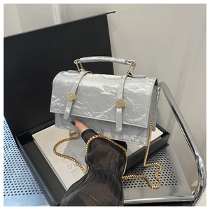 Detail of silver crinkled texture flap bag with gold chain strap and metal buckles