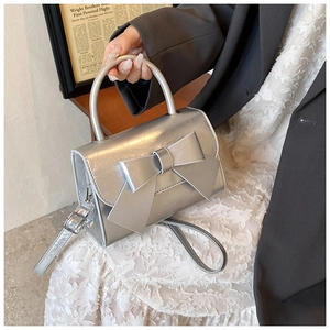 Detail of silver bow handbag with metallic finish and detachable shoulder strap