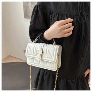 Detailed view of white quilted handbag with golden H-clasp and metallic chain strap