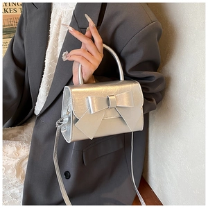 Macro view of silver metallic textured crossbody bag featuring a large decorative bow