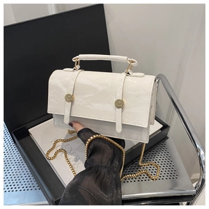 Detail of white textured leather handbag with gold chain and circular handle accents