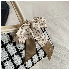 Detail of tweed tote bag featuring leopard print satin scarf tied to white leather handle
