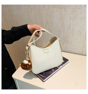 Detail of off-white crescent bag with FASHION text and brown plush monster charm decoration