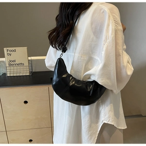 Detail of black PU leather crescent shoulder bag showing its pleated texture and soft shape