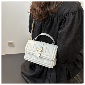 White quilted PU leather crossbody bag with gold chain strap worn with a black dress