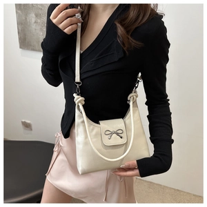 Détail du sac bandoulière en cuir verni blanc crème avec nœud argenté et poignée nouée