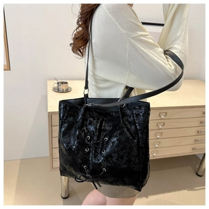 Detail of black glossy tote bag with lace-up crossing design and vintage texture