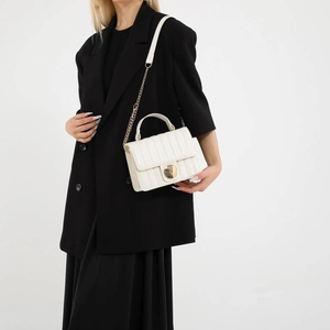 Elegant white quilted crossbody bag with gold chain strap shown on a black dress model