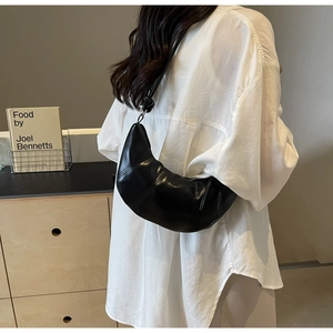 Detail of black crescent croissant bag featuring vertical stitching and a knotted strap