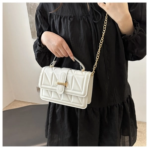 Close-up of white quilted crossbody bag with gold H-shaped lock and metal chain strap