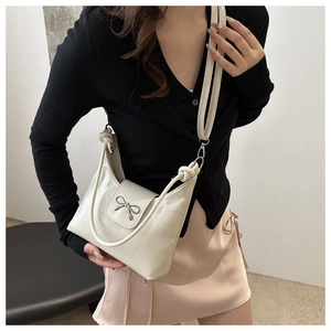 Détail du sac beige avec nœud papillon en similicuir texturé et boucle métallique chic