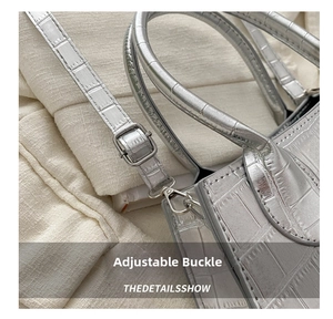 Detail of silver crocodile texture leather bag with metal buckle and adjustable strap