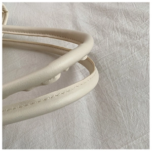 Detailed macro view of cream tote bag handle with fine stitching and leather texture