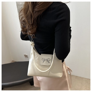 Détail du sac à bandoulière en cuir blanc cassé avec boucle nœud argentée et sangle tressée
