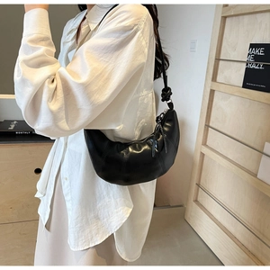 Detail of black croissant hobo bag with knotted strap and quilted faux leather finish