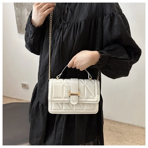 Close-up of white quilted tote with gold metal chain strap and minimalist buckle