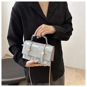 Detail of grey chain handbag showing glossy crinkled texture and golden round buckles