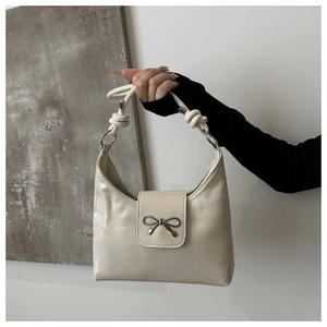 Détail du sac crème avec nœud papillon, bandoulière nouée et boucle métal