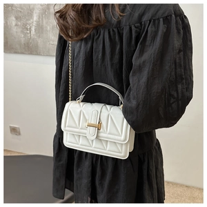Close-up of white crossbody bag with V-shaped quilting and golden metal H-lock detail
