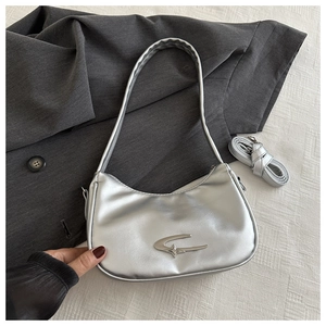 Detailansicht der silbernen Mondsichel-Tasche mit Stern-Logo und doppelten Riemen
