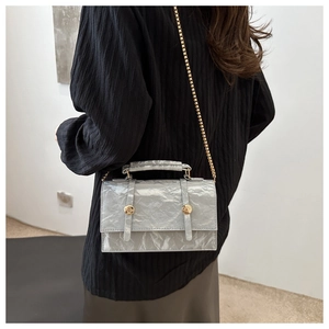 Detail of silver crinkled texture crossbody bag with gold chain strap on model