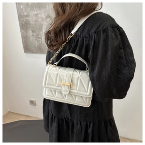Close-up of white quilted leather texture and golden metal buckle on a square handbag