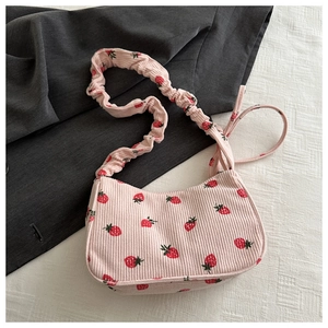 Detail of pink corduroy shoulder bag with strawberry print and ruched strap design