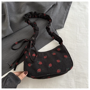 Detail of black corduroy shoulder bag with red strawberry print and ruched strap