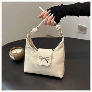 Détail du sac à main crème en cuir avec nœud papillon argenté et poignée en corde épaisse