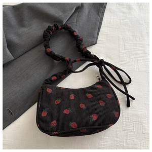 Close-up of black corduroy strawberry print bag with pleated handle and metal zipper