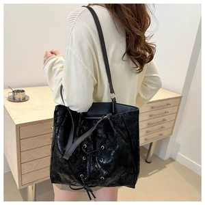 Close-up of black tote bag featuring distinctive lace-up bow design and glossy texture