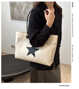 Detail of beige tote bag featuring a black star pattern and adjustable drawstring closure