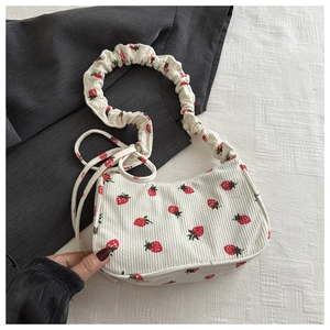 Close-up of strawberry print on white corduroy bag with stylish ruched shoulder strap