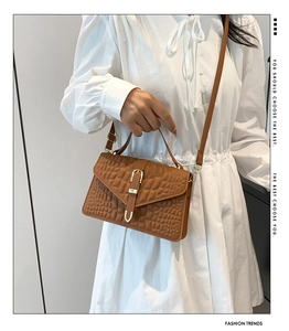 Close-up of brown crocodile texture bag with gold clasp and elegant top handle