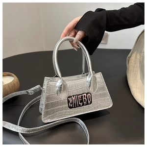 Close-up of silver crocodile embossed mini bag with ZMIEBO embroidered patch and handles