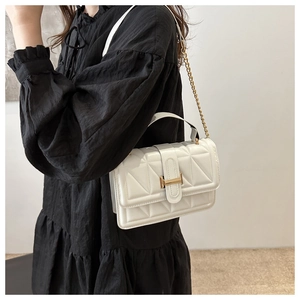 Detail of white quilted leather bag featuring a gold H-shaped clasp and chain strap