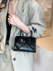 Glossy black leather bow handbag with structured square design and top handle for women