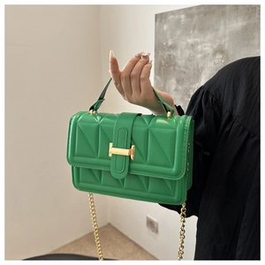 Close-up of green quilted small square bag with gold H clasp and chain strap