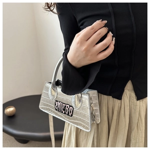 Detail view of silver crocodile textured handbag with pink ZMIEBO embroidery and shoulder strap