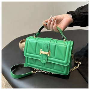 Detail of green quilted crossbody bag with golden H clasp and metal chain strap