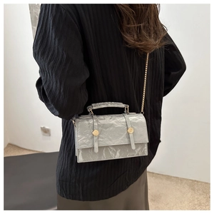 Détail du petit sac gris à texture plissée avec chaîne dorée et boutons ronds déco