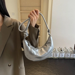 Silver metallic croissant crescent bag with knotted strap and vertical quilted details