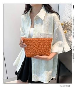 Detailed view of an orange quilted handbag with a unique textured floral pattern design