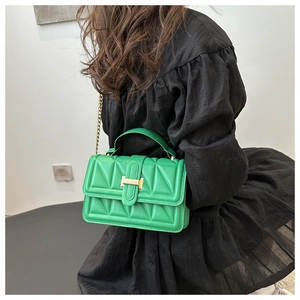 Detail view of bright green quilted handbag with golden H-clasp and metal chain strap