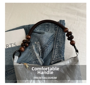 Detail of grey textured tote bag featuring brown wooden bead handles and a gold zipper